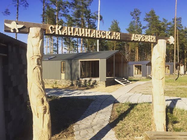 Входная группа с резной деревянной вывеской «Скандинавская деревня»
